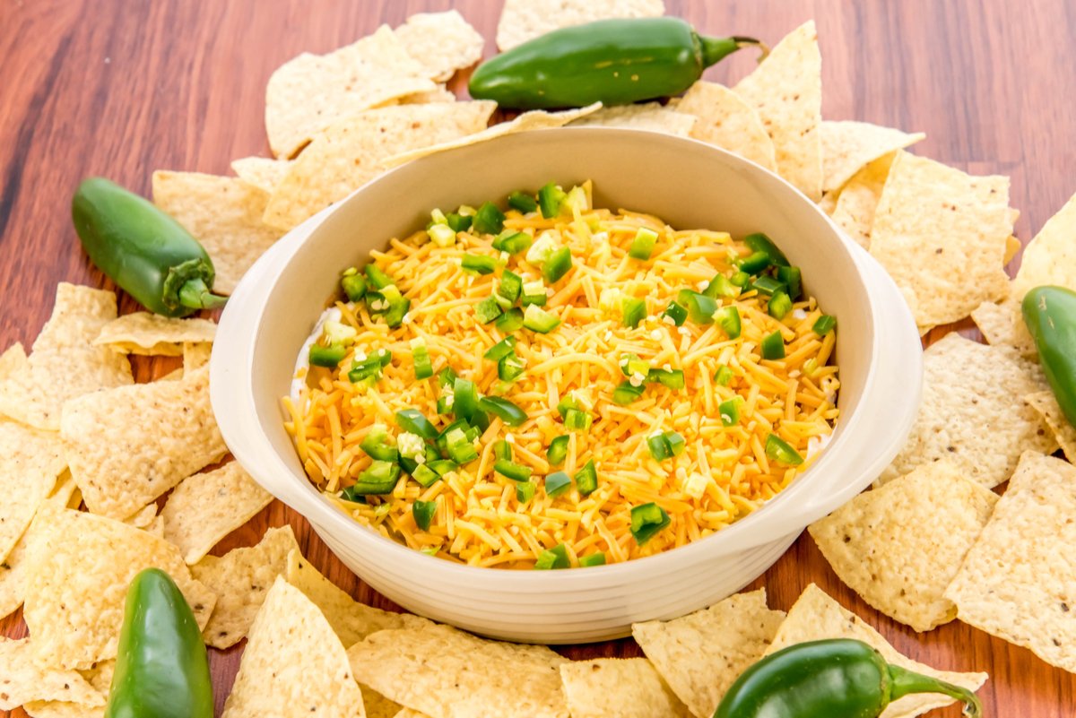 Gooey bowl of bean dip with nacho cheese on top